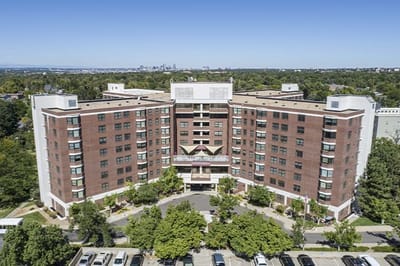 Aerial view of a senior living facility building surrounded by trees
