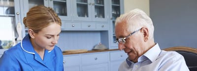 Caregiver assisting an older adult in a cozy interior setting