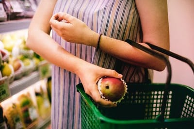 A person holding a fruit in a grocery store
