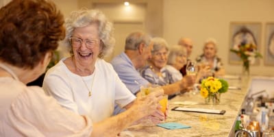 Residents enjoying drinks and laughing at a common area bar