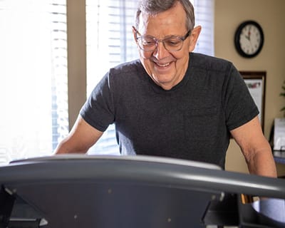 Elderly man smiling while using a treadmill