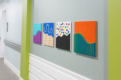 Colorful art pieces displayed on a facility hallway wall