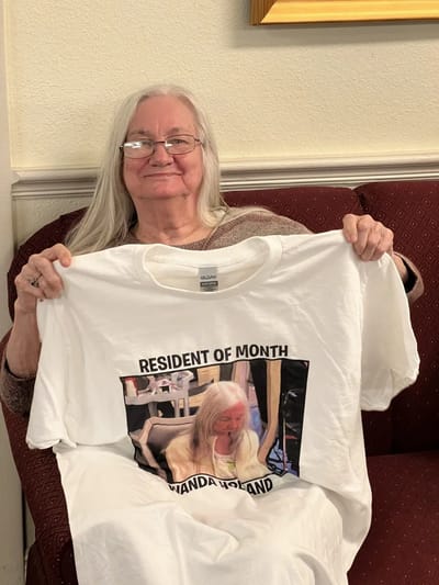 Resident holding a 'Resident of the Month' t-shirt