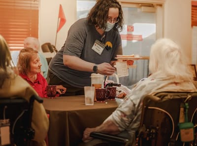 Staff serving food to residents in a common area