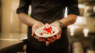 A staff member holding a dessert dish