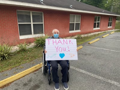 Resident in a wheelchair holding a thank you sign