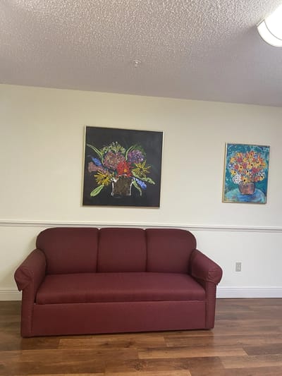 Cozy common area with a red couch and floral paintings