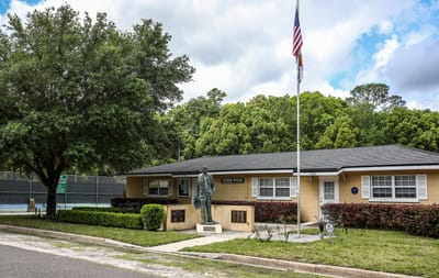 Exterior view of a senior living facility with flag and statue