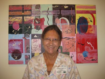 Staff member smiling in front of colorful artwork