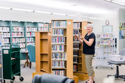 A staff member organizing books in the library