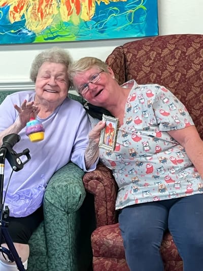 A resident and staff member smiling together in a common area
