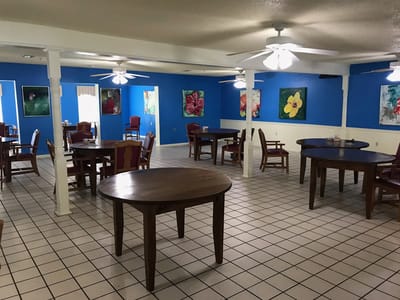 Bright dining area with tables and colorful paintings