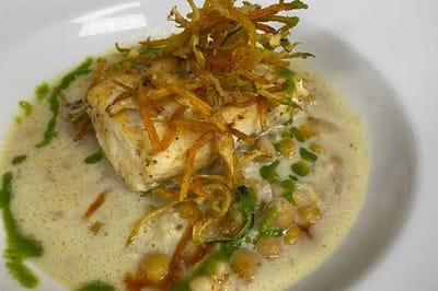 A gourmet meal plate featuring fish and garnishes