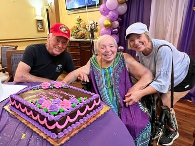 Celebration with residents and staff around a birthday cake
