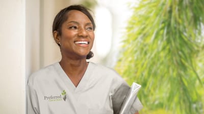 A staff member smiling outdoors, holding a clipboard