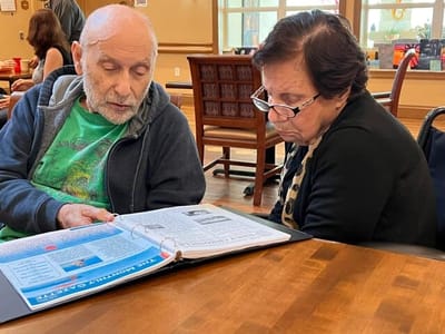 Two residents engaged in conversation over a scrapbook