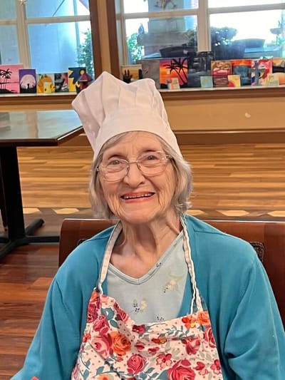 Resident in a chef's hat with an apron smiling