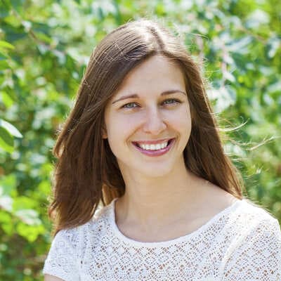 Smiling young woman outdoors with greenery in the background