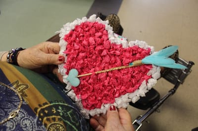 Resident holding a heart-shaped craft project