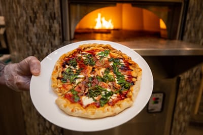 A resident holding a freshly baked pizza in a dining area