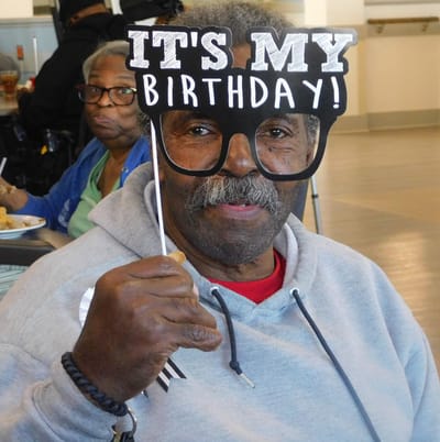 Resident celebrating birthday with festive sign