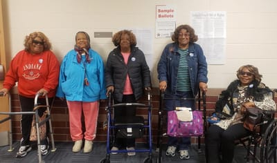 Five women with walkers at a community event