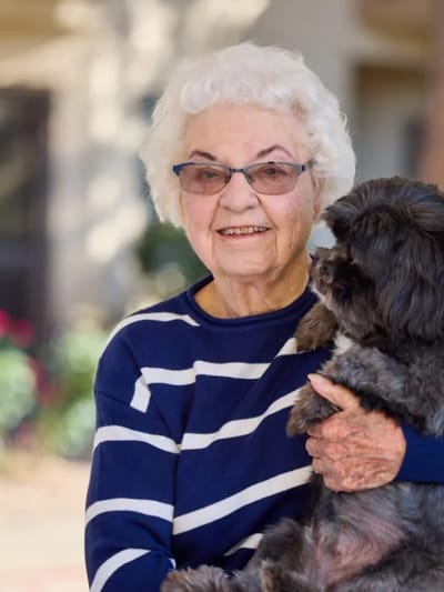 Senior woman holding a small dog outdoors