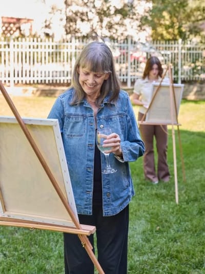 Residents painting outside in a garden setting.