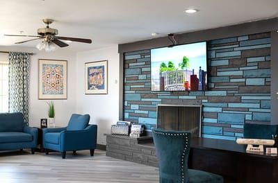 Common area with blue chairs and a stone accent wall.