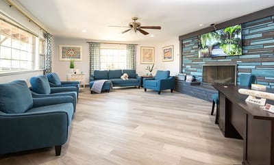 Bright common area with blue seating and fireplace.