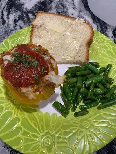 Stuffed bell pepper, green beans, and bread on a plate.