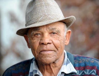 Close-up portrait of an elderly man wearing a hat.