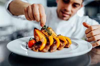 Chef plating a gourmet meal in a kitchen