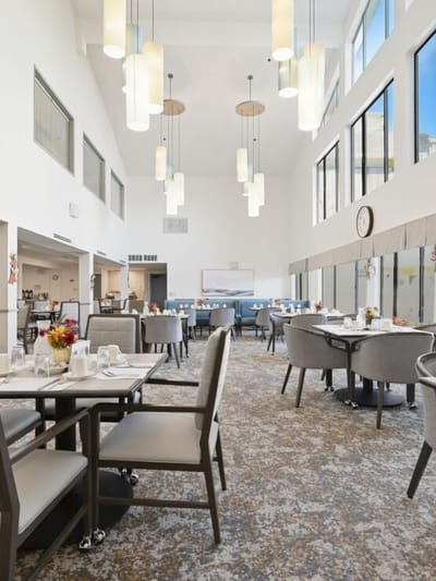 Modern dining area with large windows and tables set for meals.