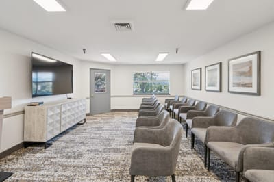 Empty waiting area with gray chairs and TV