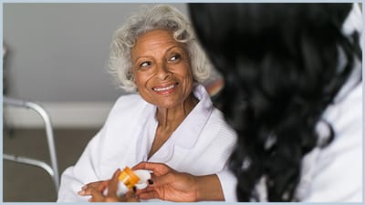 A caregiver assisting an elderly woman with medication