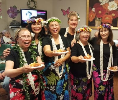 Residents celebrating with leis and food in a cheerful common area