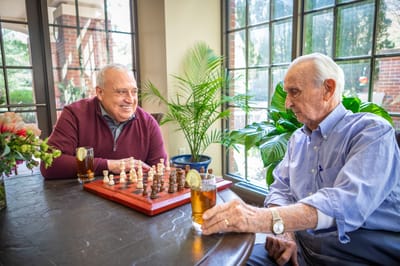 Two residents enjoying a game of chess in a cozy common area