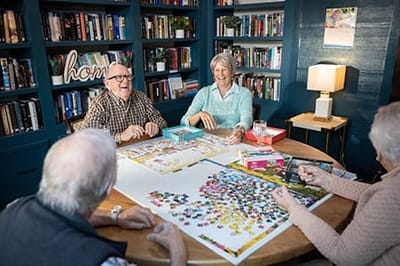 Residents engaging in a puzzle activity in a cozy common area