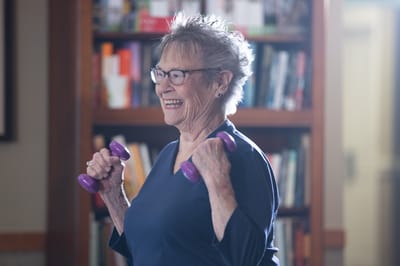 A senior woman exercising with dumbbells in an activity room