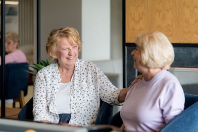 Two women laughing and enjoying a conversation indoors