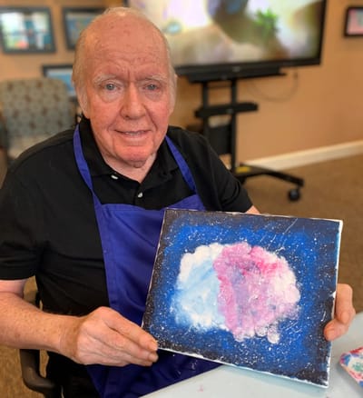 Resident proudly holding artwork in a common area