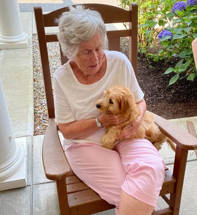Resident holding a small dog on a porch