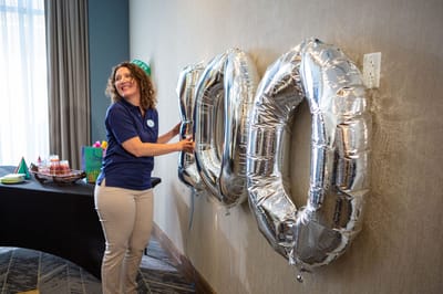 Staff member celebrating with silver balloons.