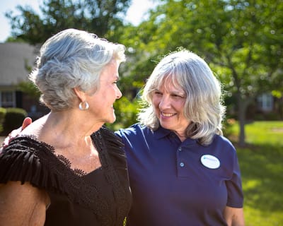 Staff member smiling with resident in a sunny garden