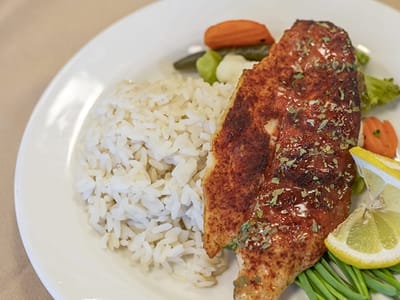 A plated meal with fish, rice, and vegetables