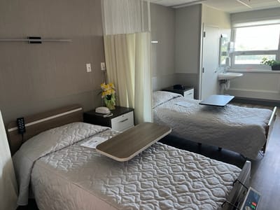 Two hospital beds in a patient room with a window.
