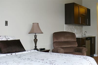 Cozy bedroom setup with a chair and kitchenette