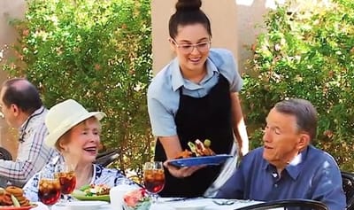Staff serving food to residents outdoors at a dining area