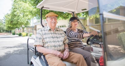 Residents enjoying a ride in a golf cart outside